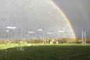 A double rainbow image with raindrops scattered on the window