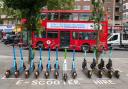 E-scooters lined up across from a red London bus. Credit: PA