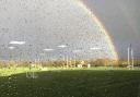 A double rainbow image with raindrops scattered on the window