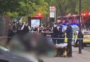 Police at Stamford Hill while paramedics treat a woman